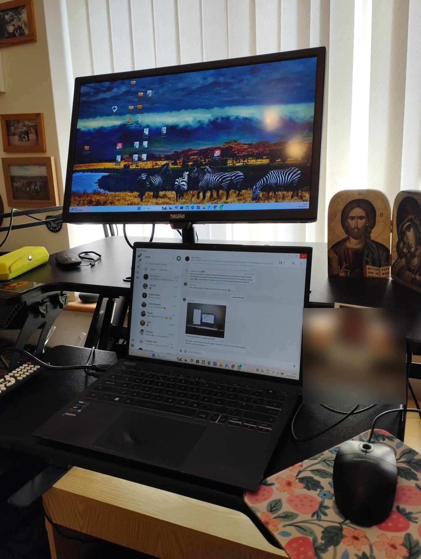 A standing desk with a laptop and a large monitor.