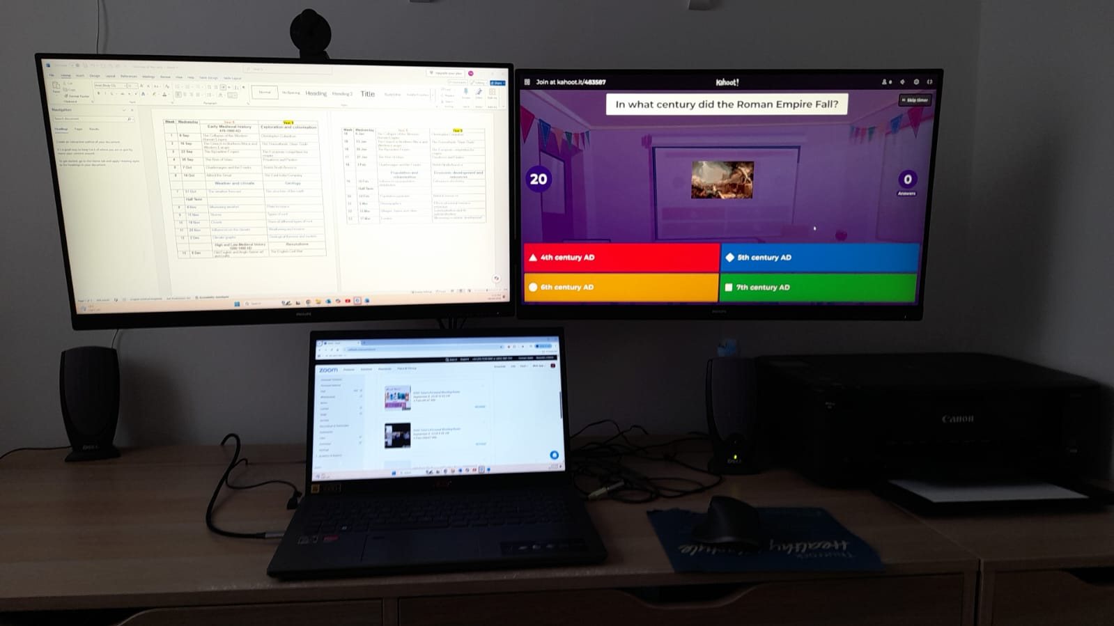 A desk with two monitors and a laptop, set up for a live lesson.