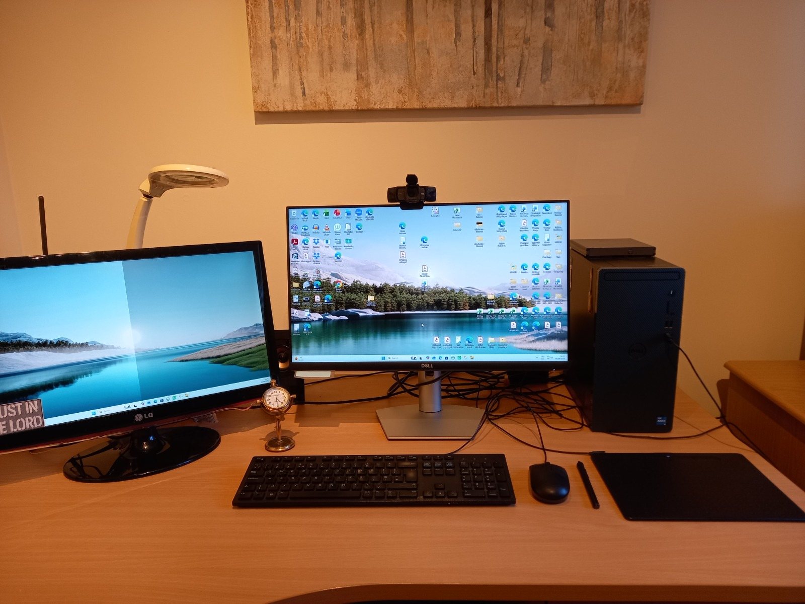 A wooden desk with two monitors and a small clock.